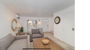 A modern living room with a sofa, armchair, and a coffee table. There is a mirror on the wall, a lamp, and a door in the background. - Hersheypark in 2 miles,w/ large private yard (Hershey)