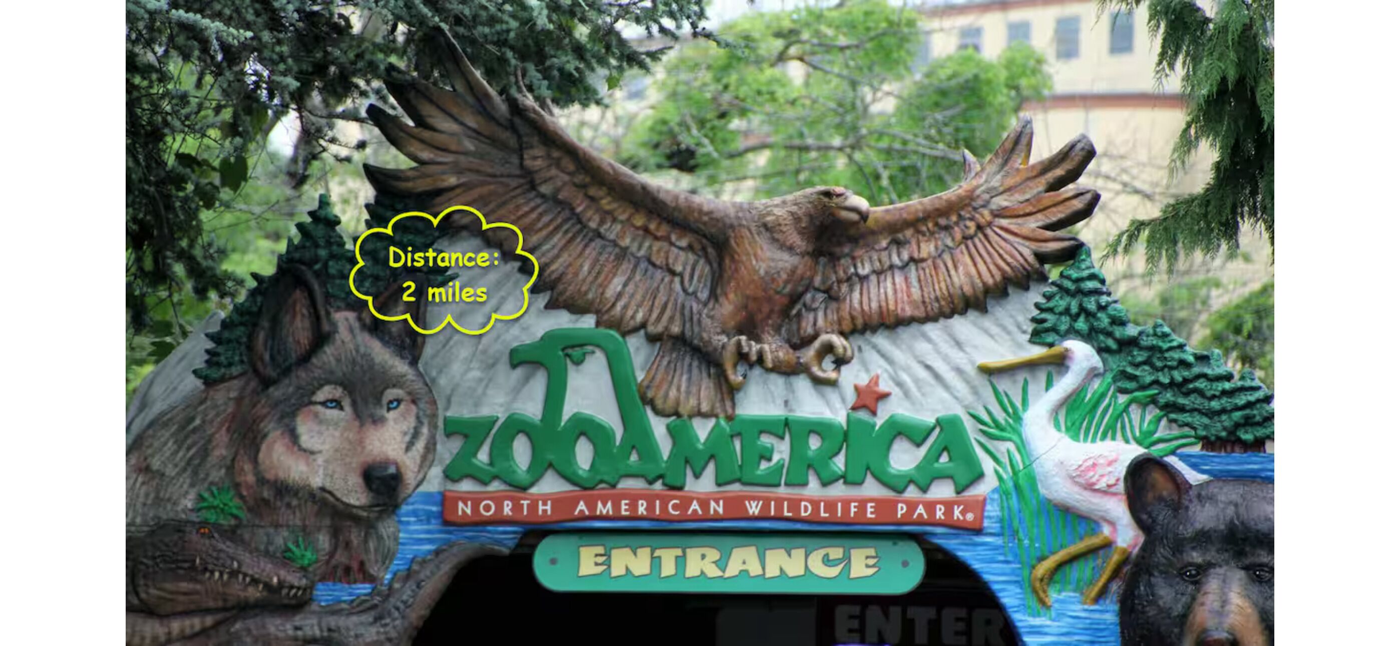 Ingresso di uno zoo con una grande scultura di aquila, un orso e un lupo.
