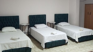 A room with three single beds, each with a white bedspread and a dark headboard. There are bedside tables with lamps and a wooden wardrobe in the corner. - Timo Pyramids View : Deluxe Triple Room (Giza Governorate)