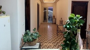 A hallway with checkered flooring, a ceiling light fixture, and a potted plant. - Timo Pyramids View : Deluxe Triple Room (Giza Governorate)