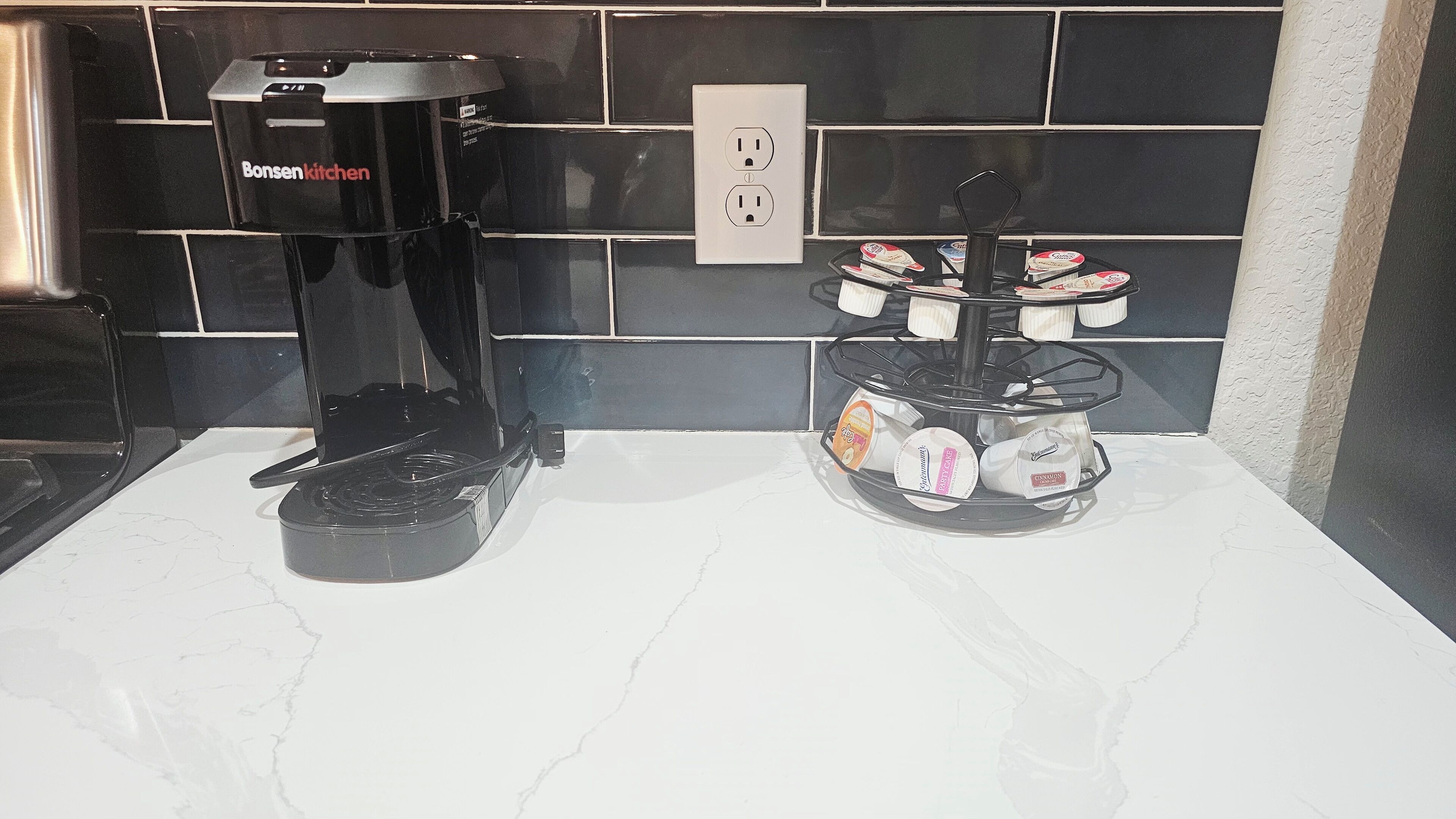 Una cafetera y un soporte para tazas con varias tazas sobre una encimera.