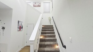 Eine Treppe mit weißer Handlauf, Teppichstufen und einer Wandleuchte.