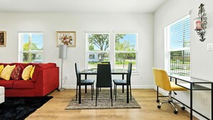 Ein modernes Wohnzimmer mit einem roten Sofa, schwarzen und gelben Stühlen, einem Glastisch und einem gelben Bürostuhl.