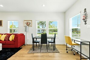 Ein modernes Wohnzimmer mit einem roten Sofa, schwarzen und gelben Stühlen, einem Glastisch und einem gelben Bürostuhl.