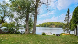 Une cour verdoyante avec un lac, des arbres et un quai.