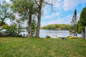 A grassy yard with a lake, trees, and a dock. - Chalet Petit Bonheur - Waterfront (beautiful beach) - Fully equipped (Val-des-Bois)