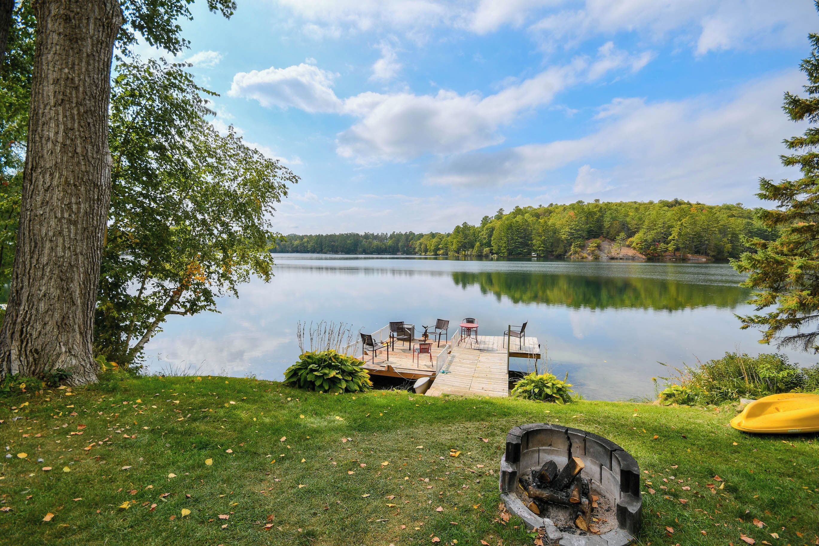 A lakeside deck with outdoor seating and a fire pit.