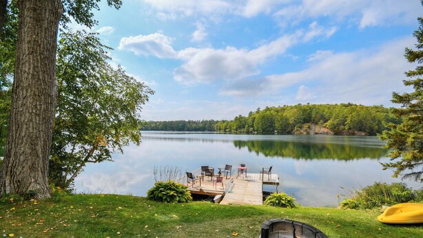 Une terrasse au bord du lac, avec des sièges d’extérieur et un foyer.