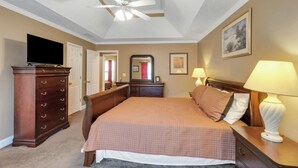 A bedroom with a bed, dresser, TV, ceiling fan, and artwork on the walls. - 6BR Home • Spacious Yard + Grill • Peaceful Suburb (Locust Grove)