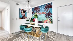 Un comedor con una mesa blanca, sillas color turquesa y un mural grande en la pared.