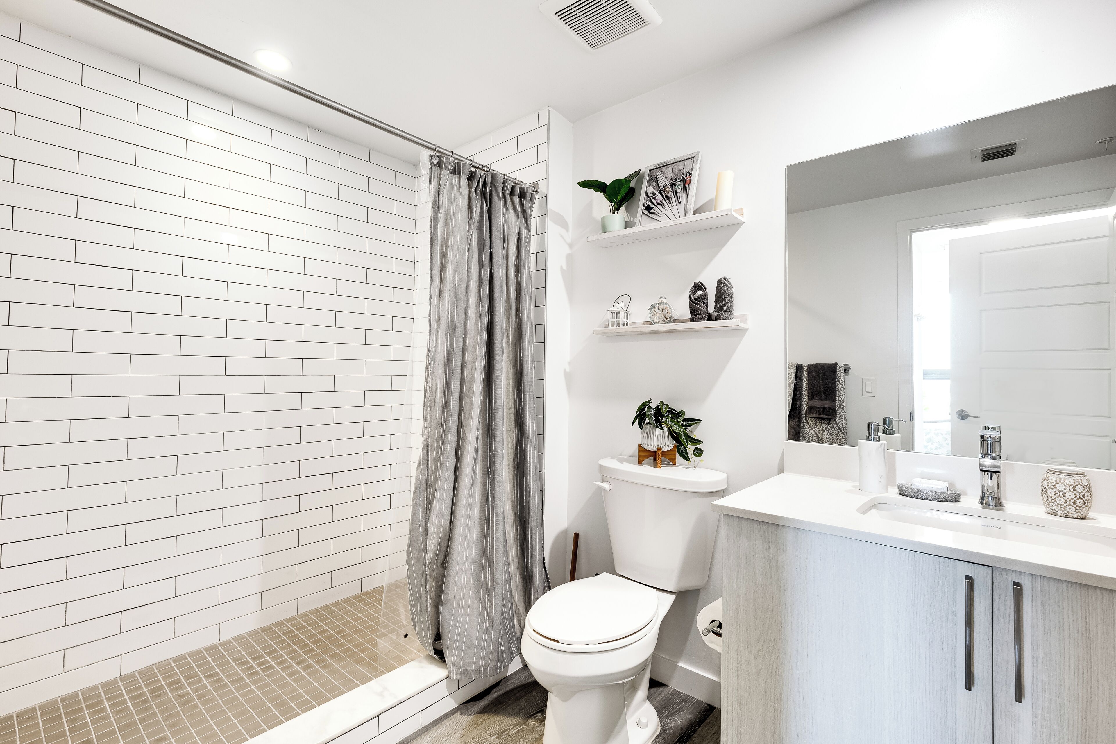 A modern bathroom with a shower, toilet, and sink.