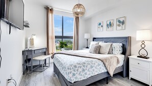 Un dormitorio moderno con una cama grande, mesitas de noche, un escritorio y un televisor.