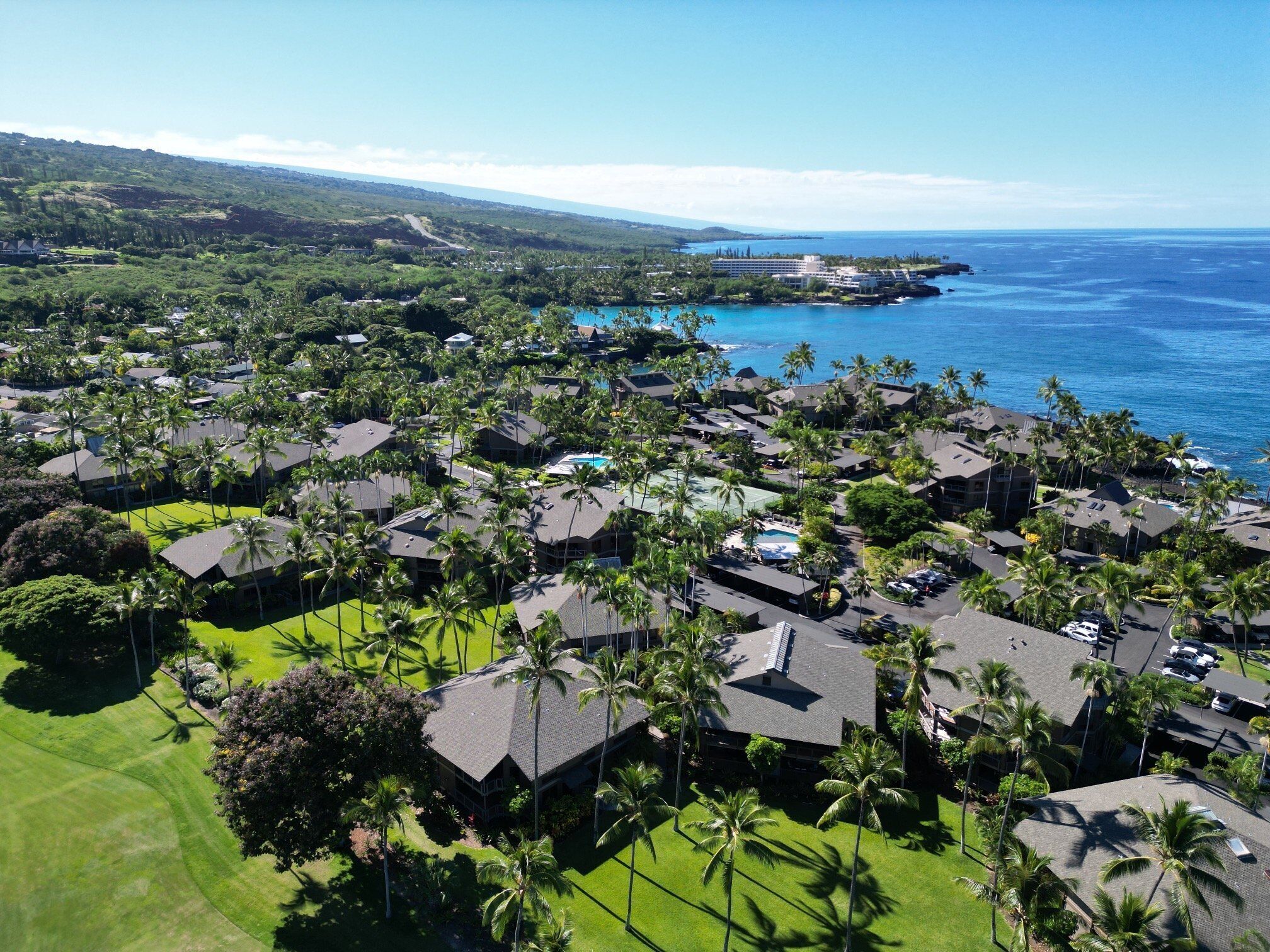 Ein Luftbild eines Küstenresorts mit mehreren Gebäuden, üppigem Grün und freiem Blick auf den Ozean.