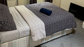 Una camera da letto con due letti, un termosifone, tende, una finestra con tende in pizzo e una parete con un quadro incorniciato.