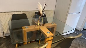 Un tavolo da pranzo con piano in vetro e gambe in legno, accompagnato da due sedie.