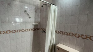 A bathroom with a shower, toilet, and a towel rack.
