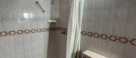 A bathroom with a shower, toilet, and a towel rack.