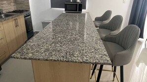 Una cocina moderna con encimeras de granito, una isla central y un comedor con dos sillas.
