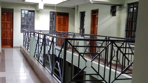 Un pasillo de hotel con barandilla de vidrio, puertas de madera y suelo de baldosas.