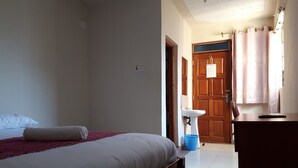 Una habitación de hotel con cama, escritorio, lavamanos y puerta de madera.