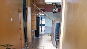 Un pasillo con suelo de madera, una planta en maceta y una escalera que sube a un nivel superior.