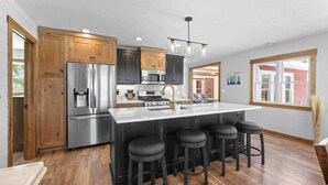 A modern kitchen with a central island, stainless steel appliances, and wooden cabinets. - Mallard Lake Retreat (Jackson)