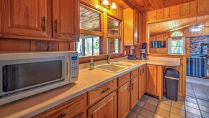 Une cuisine rustique, située dans une cabane en bois, équipée d’un four à micro-ondes, d’un évier et d’une machine à café.