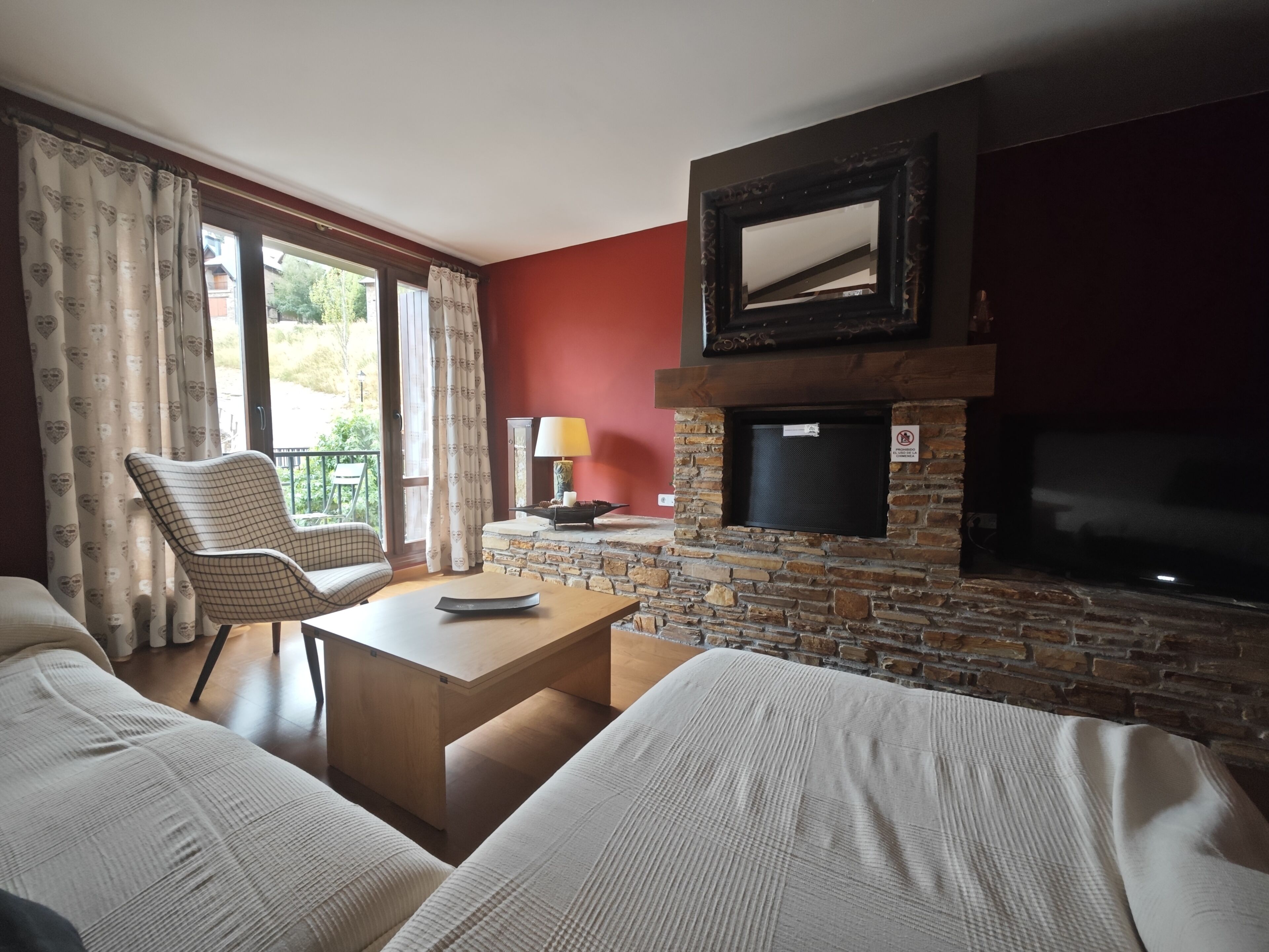 A living room with a stone fireplace, a television, a sofa, a chair, and a table.