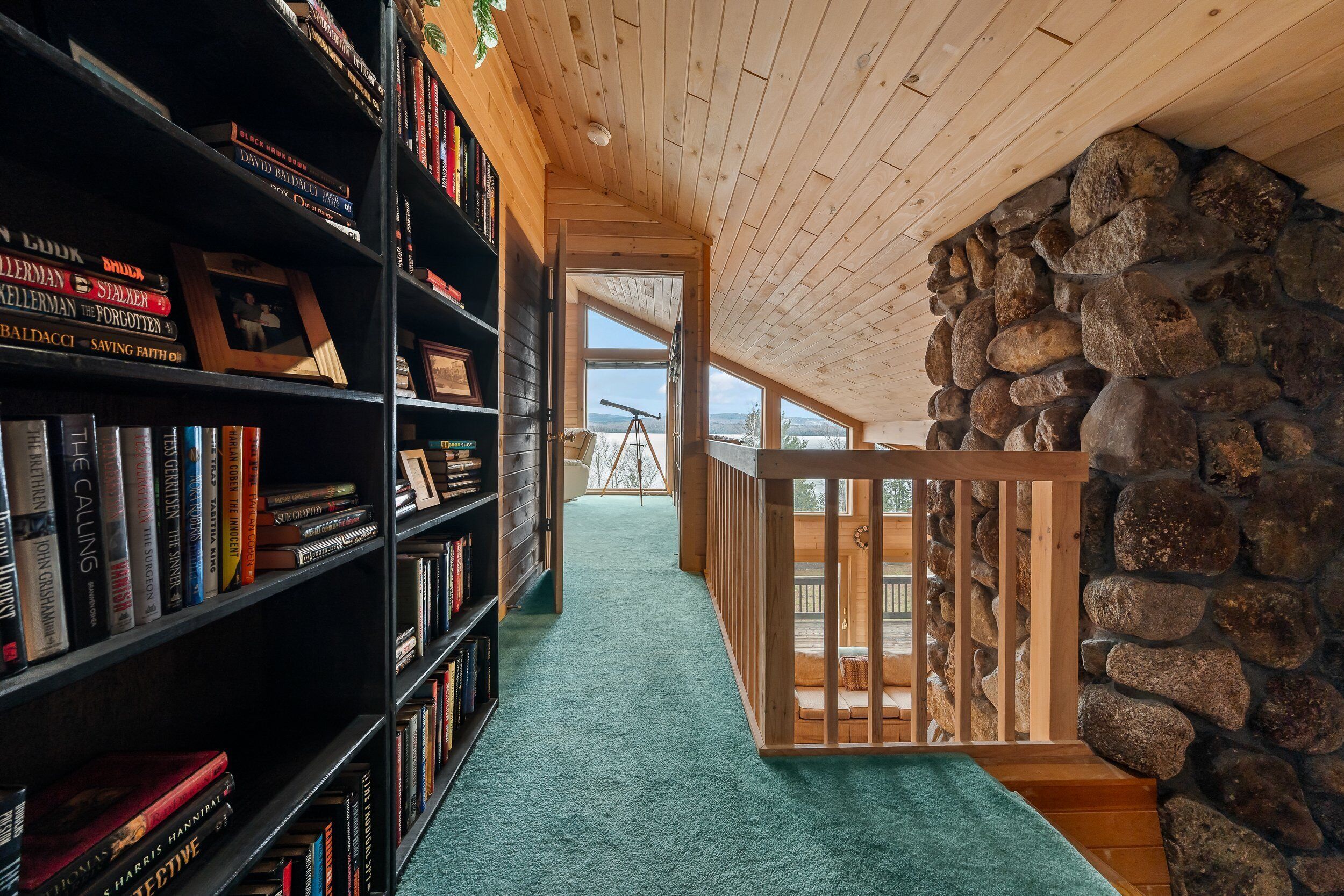 Una biblioteca con estanterías, un telescopio y un muro de piedra.
