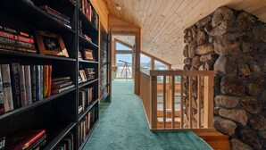 A library with bookshelves, a telescope, and a stone wall. - Buckfield Lakehouse | Private waterfront on Rangeley Lake (Rangeley)