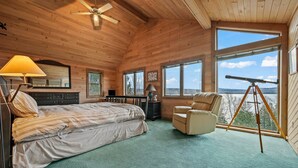 A cozy bedroom with a bed, a chair, a desk, and a telescope. - Buckfield Lakehouse | Private waterfront on Rangeley Lake (Rangeley)