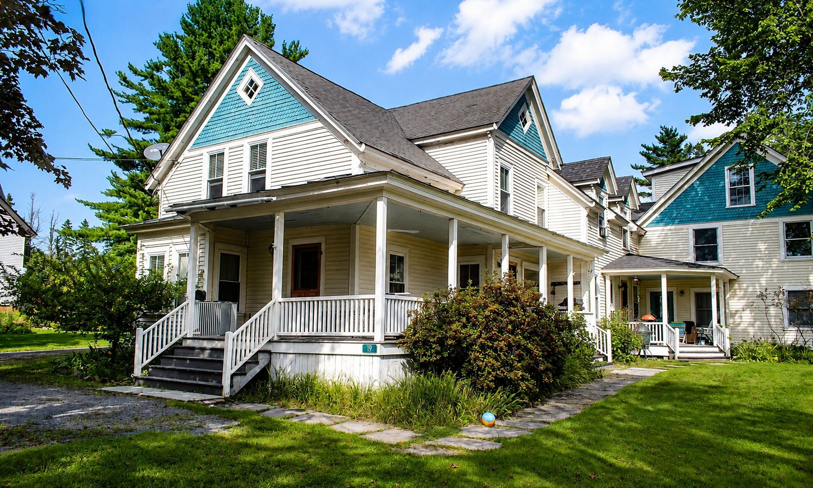 A two-story house with a front porch, a visible staircase, and a well-maintained lawn.