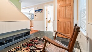 A hallway with a wooden door, a bench, and a patterned rug. - Downtown Crossing Condo | Walk to Town | Pet Friendly | Close to Saddleback (Rangeley)