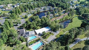 Vista aérea de um bairro residencial com casas, piscina e um edifício grande.