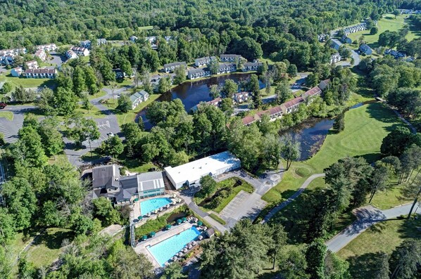 Une vue aérienne d’un quartier résidentiel avec des maisons, une piscine et un grand immeuble.