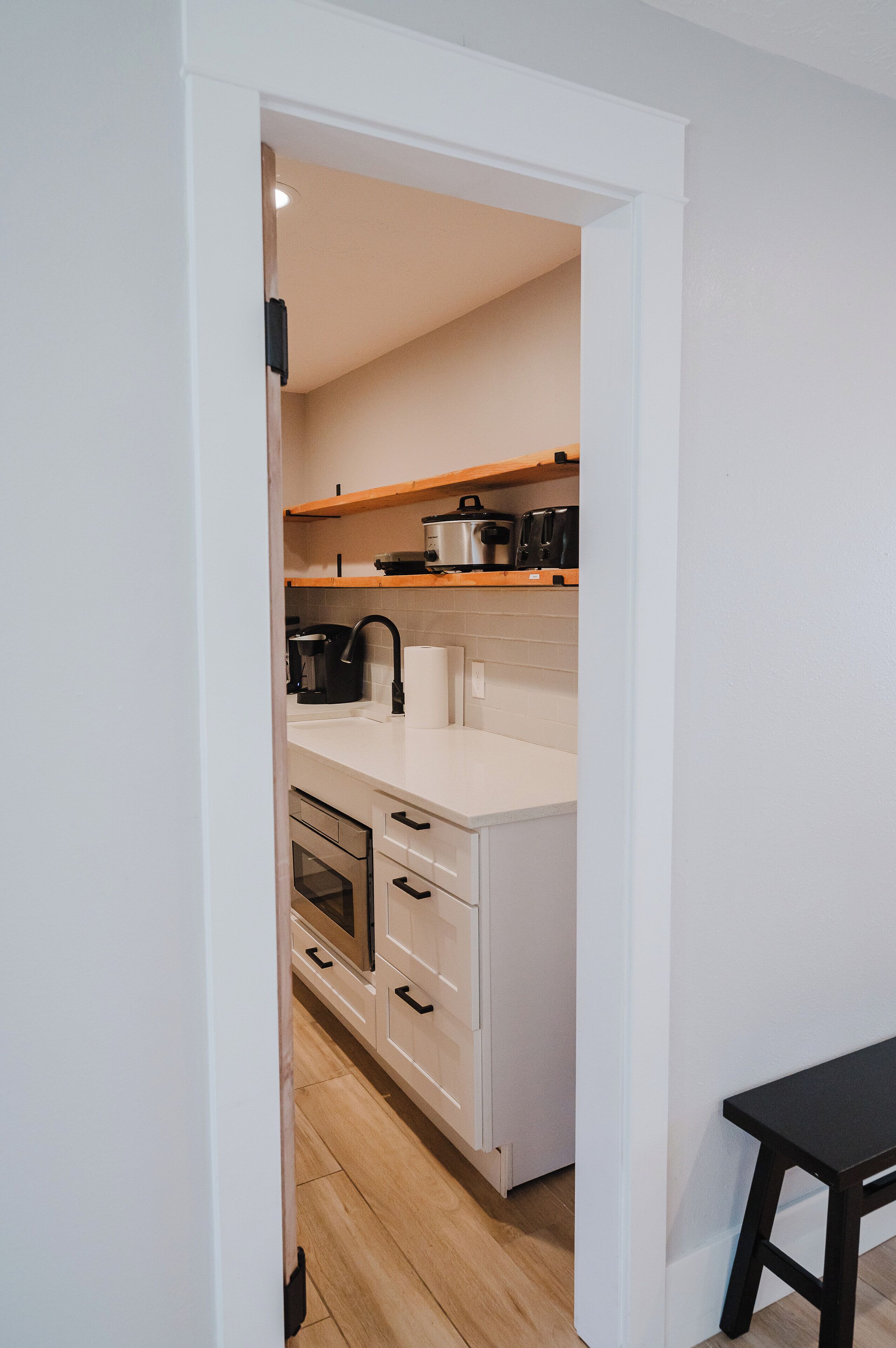 A modern kitchen with white cabinetry, a wooden countertop, and a black faucet.