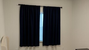 A bedroom with a bed, a window with dark curtains, a small desk, and a carpeted floor. - Lovely studio in charming Hanford perfect for getaway (Hanford)