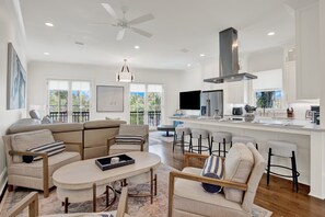 A modern kitchen with white cabinetry, a central island, and a ceiling fan. - Live in Luxury at This Brand New Tybee Island Escape | Heated Pool Access (Tybee Island)