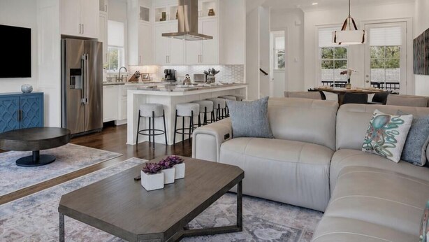 A modern living room with a sofa, coffee table, and bar stools. - Live in Luxury at This Brand New Tybee Island Escape | Heated Pool Access (Tybee Island)