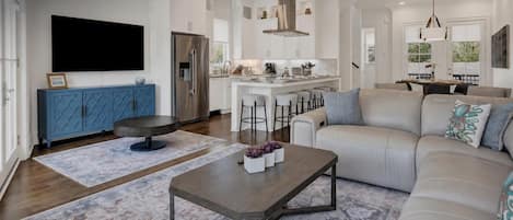 Un salon moderne avec un canapé, une table basse et des tabourets de bar.