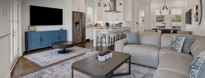 A modern living room with a sofa, coffee table, and bar stools. - Live in Luxury at This Brand New Tybee Island Escape | Heated Pool Access (Tybee Island)