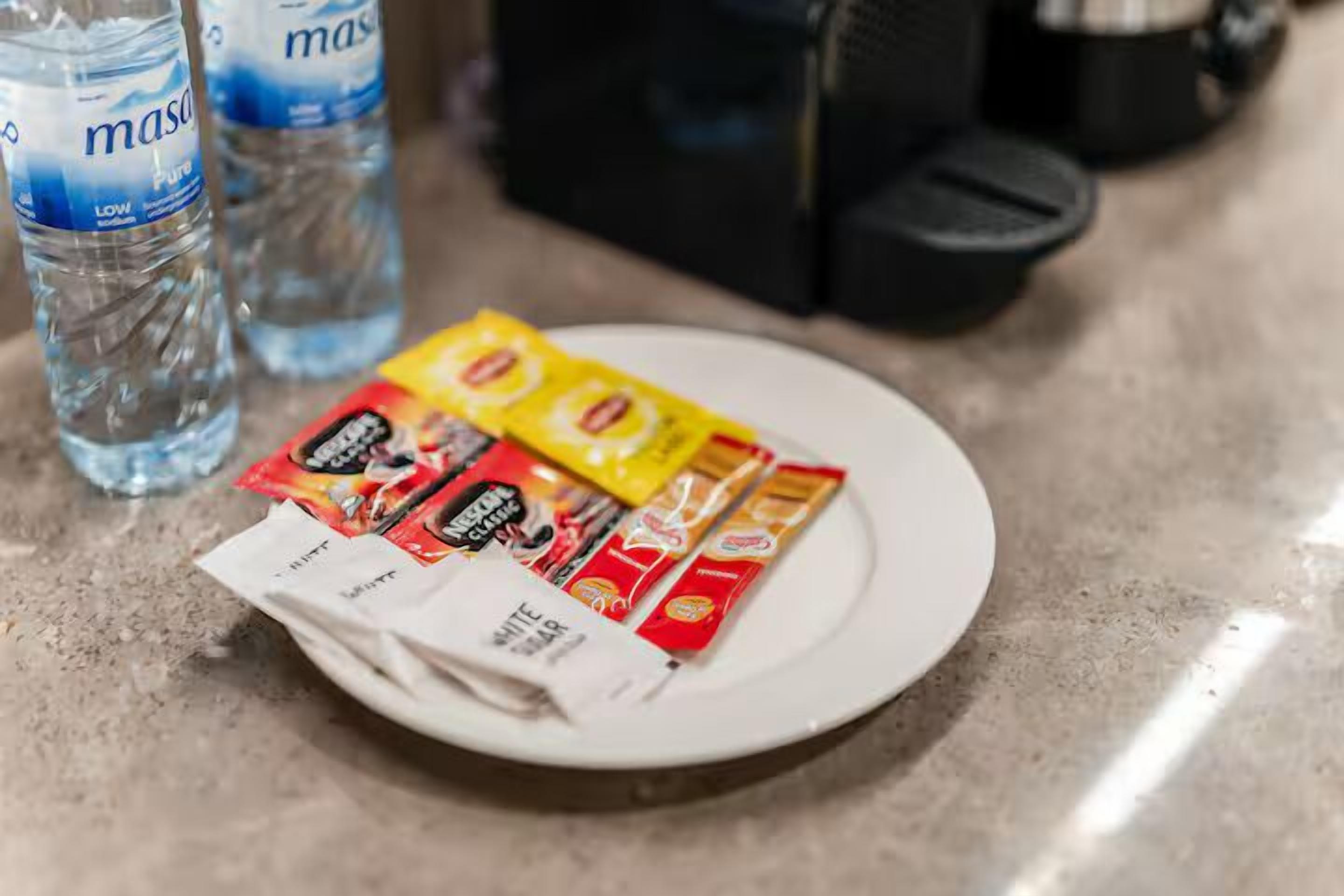 Un plat amb diversos estris de menjar i una ampolla d'aigua damunt un taulell.
