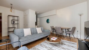 En moderne stue med en grå sofa, et sofabord og et spiseområde med stole.