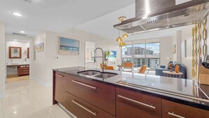 A modern kitchen with a large island, stainless steel appliances, and a view of the city. - Luxury Penthouse with City and Canal View (Miami)
