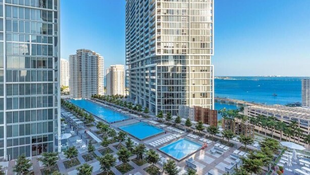 A high-rise building with a rooftop pool and a view of the sea. - Luxury Penthouse with City and Canal View (Miami)