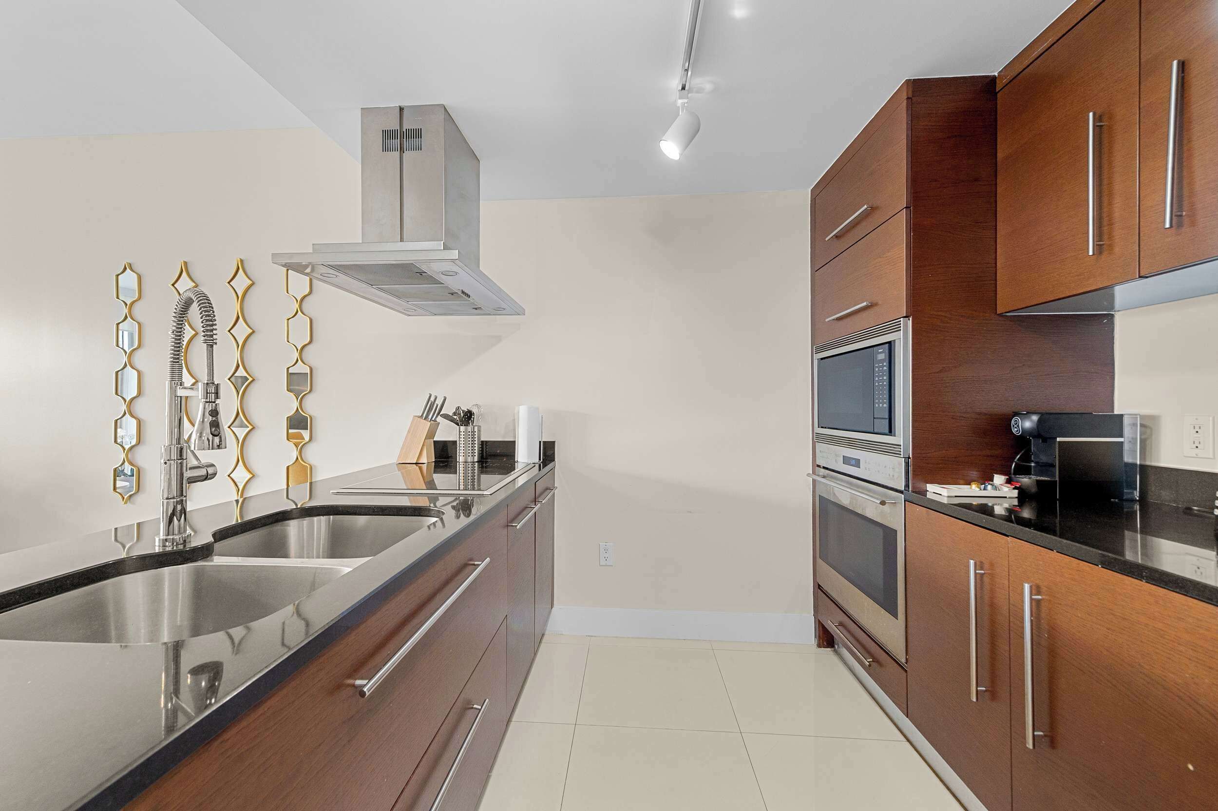 A modern kitchen with stainless steel appliances, wooden cabinets, and a built-in oven.
