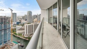 A high-rise building with a balcony overlooking a cityscape, including construction cranes and a river. - Luxury Penthouse with City and Canal View (Miami)