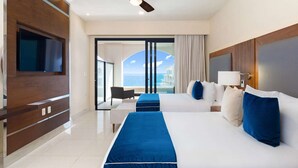 Une chambre d’hôtel avec un grand lit, une télévision, un ventilateur de plafond et une vue sur la mer.