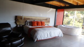 A modern bedroom with a large bed, a leather chair, and a bathtub. - Acento House (Valle de Bravo)