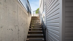 Una escalera de concreto estrecha con barandales metálicos que lleva a un área amurallada.